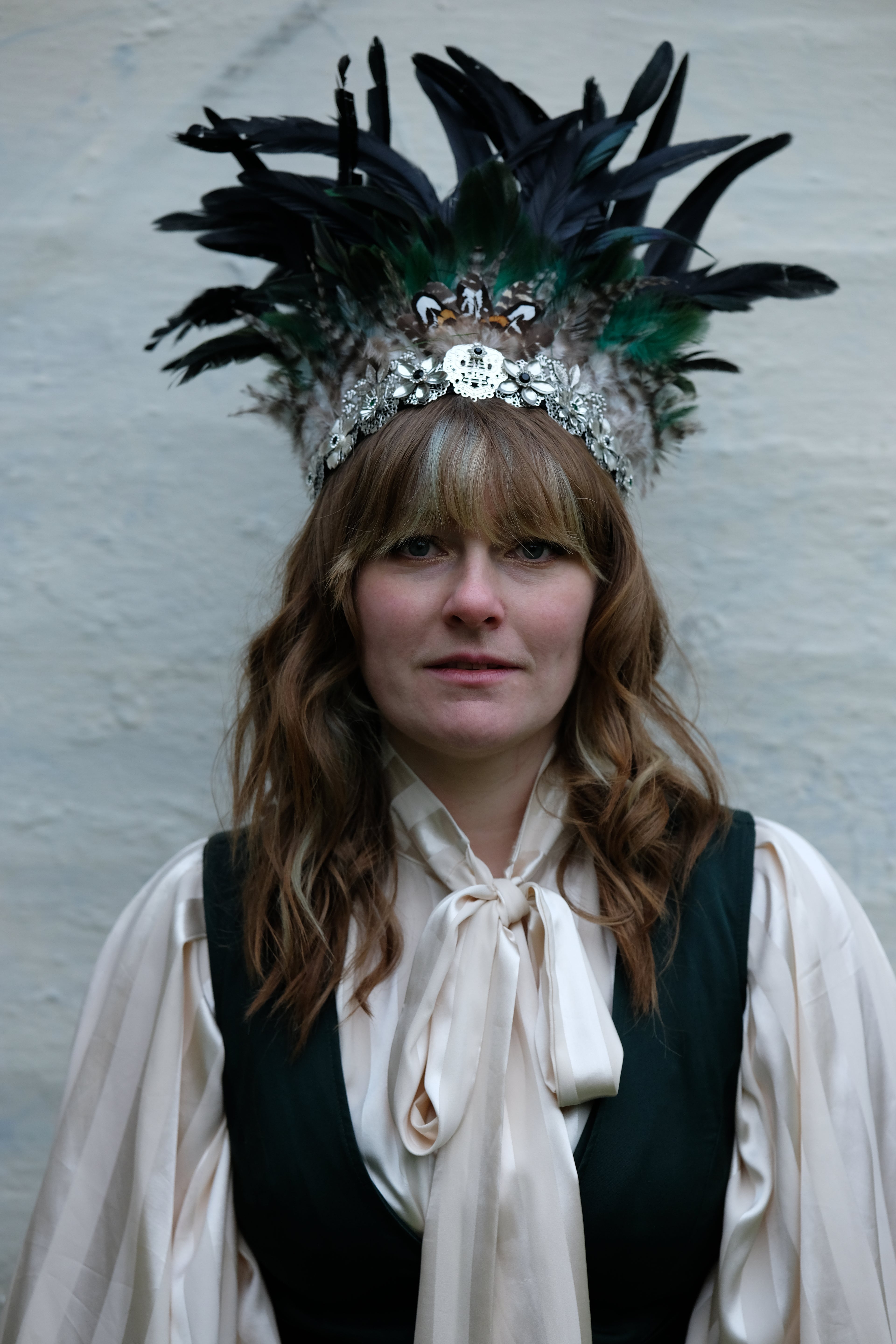 Person wearing a feathered headpiece against a plain background